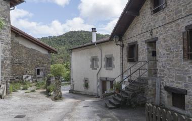 Agorretako (Nafarroako Pirinioak) harrizko eraikin tradizionalen multzoa, Pirinioetako landa-arkitektura eta atzean basoa dituena.
