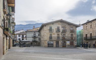 Plaza principal de altsasu rodeada de edificios de piedra con montaña de fondo.