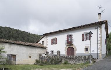 Arquitectura tradicional de Antxoriz en el Pirineo, con fachada blanca, contraventanas de madera roja y muros de piedra.