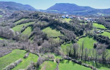 Pueblo de Arce en valle verde rodeado de montes boscosos y prados naturales.