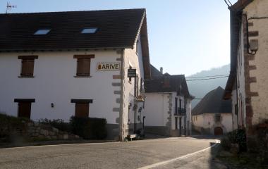 Calle de Aribe con casas de piedra blanca y cartel de pueblo de Aribe.