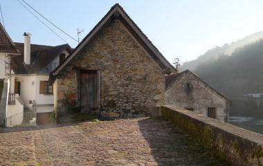 Casas de piedra tradicionales en Aribe con arquitectura pirenaica, rio y montes boscosos de fondo.