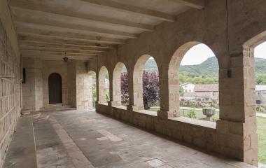 Claustro de piedra con arcos  en Arrieta, Pirineo navarro, vistas a pueblo y montaña.