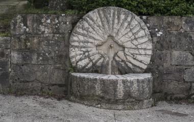Fuente de piedra con caño circular en Azparren, Pirineo de Navarra, integrada en muros de sillería.