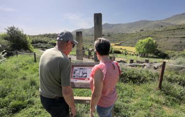 Dos turistas observan cartel informativo del yacimiento de Santa Criz de Eslava.