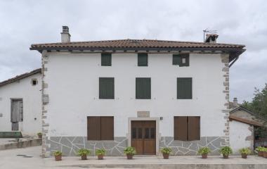 Casatradicional de Esnoz con fachada blanca, piedra en esquinas y planta baja.