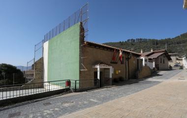 Plaza de Ezprogui con edificios tradicionales de piedra y fronton de una pared verde.
