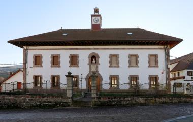 Garaioko udaletxea. Fatxada zuria, erloju gorria eta Pirinioetako arkitektura tradizionala ditu, harriztatutako plazan.