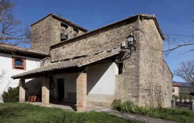 Portada de piedra con puerta de madera en Urraul Bajo, flanqueada por columnas estriadas y decoración geométrica.