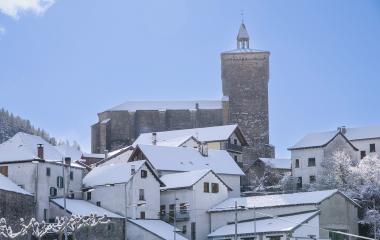 Iglesia con campanario de piedra domina el paisaje nevado de Isaba, rodeada de casas blancas tradicionales pirenaicas.