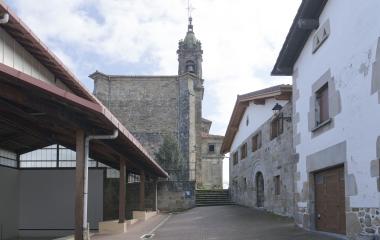 Iglesia de piedra con campanario en Iturmendi, rodeada de casas tradicionales al lado del fronton.