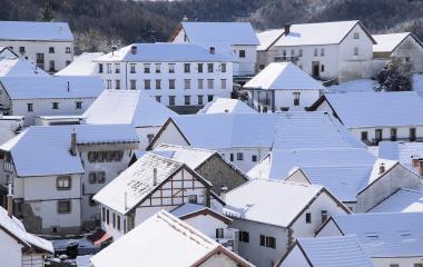 Vista aérea de Jaurrieta cubierto de nieve con casas de tejados azules y arquitectura tradicional pirenaica.