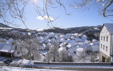 Pueblo de Jaurrieta cubierto de nieve con casas tradicionales y montañas nevadas al fondo en invierno.