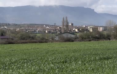 Pueblo de Lakuntza visto desde campos con montañas de fondo.