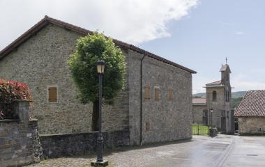 Calle empedrada de Lenaroz con arquitectura rural pirenaica de piedra gris, iglesia parroquial al fondo.