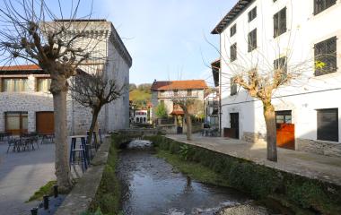 Rio atraviesa el pueblo de Lesaka con casas de piedra y torre a los lados.