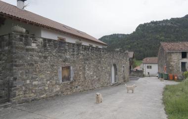 Construcciones de piedra tradicionales en Loizu (Pirineo) con montaña boscosa al fondo.