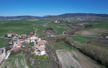 Vista aérea del pueblo de Longuida rodeado de prados verdes y montes.