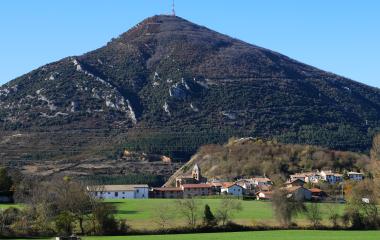 Pueblo de Monreal con iglesia al pie de monte boscoso.