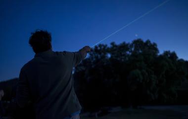 Persona señalando el cielo nocturno estrellado desde la Mesa de Interpretación de Estrellas de San Zoilo en el Sendero Urdina.