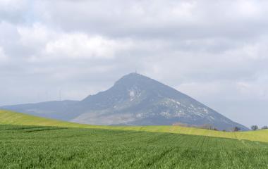 Prado verde delante de la Higa de Monreal, que tiene a su lado molinos de viento.