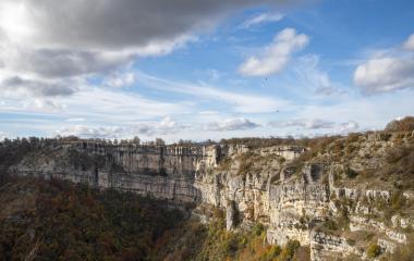 Cortados calizos verticales de la Sierra de Urbasa con bosque caducifolio en otoño bajo cielo nublado.