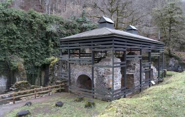 Estructura rehabilitada de la Fábrica de Armas de Eugi con muros de piedra original y cubierta metálica moderna, integrada en bosque de hayas.