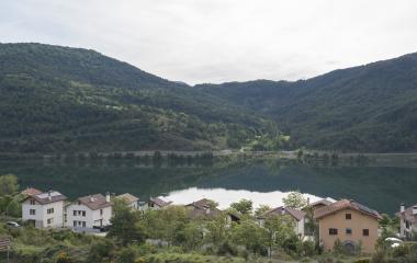 Pueblo de Nagore junto al pantano con casas tradicionales y bosque en valle pirenaico.