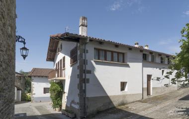 Calle de Olaibar con arquitectura tradicional de piedra y fachada blanca, en Plazaola-Sakana-Ultzamaldea.