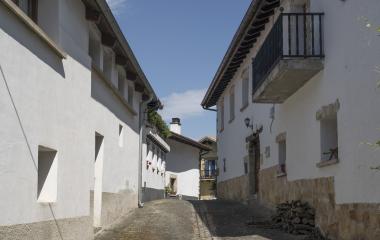 Calle empedrada de Olaibar con caseríos tradicionales de arquitectura vasco-navarra, paredes blancas y balconadas de madera.