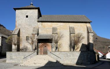 Iglesia de piedra con torre campanario en Orbara, construida en piedra de tonos claros y cubierta de pizarra oscura.