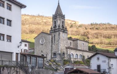 Iglesia del pueblo con campanario destacando sobre las viviendas en Almandoz.