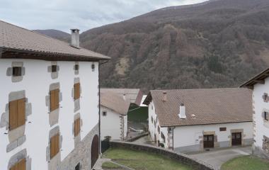 Monte detrás de conjunto de casas tradicionales en Ezkurra.