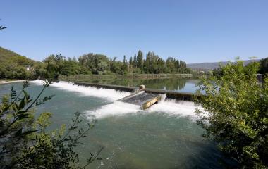 Presa del río Aragón en Paseo Cantolagua con agua en cascada blanca, vegetación  y montaña al fondo en Sendero Urdina.