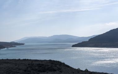 Panorámica del embalse de Yesa con montañas boscosas a ambos lados y cielo despejado.