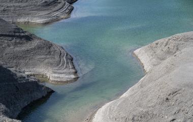 Embalse de Yesa con aguas turquesas y formaciones rocosas grises.