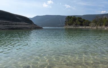 Embalse de Yesa con aguas cristalinas y montañas boscosas.