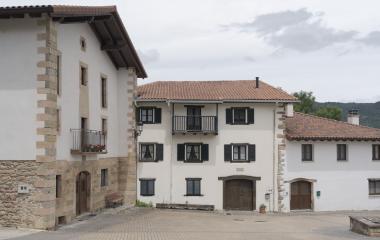 Caseríos tradicionales de piedra arenisca y blanco en Saragüeta, Pirineo navarro, con balconadas y tejados de teja curva.