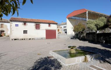 Plaza de Unciti con fuente tradicional, arquitectura rural de piedra y tejadillo rojo.