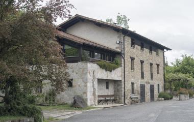 Edificio de piedra y hormigón con vegetacion alrededor en el pueblo de Urdaniz.