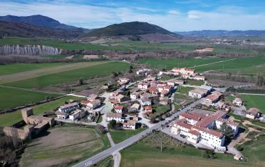 Vista aérea de Urraul Bajo con casas, iglesia, campos verdes y montes al fondo en Sanguesa.