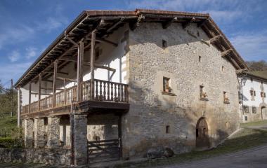 Casa de piedra tradicional en Imoz con balconada de madera y tejado de barro.