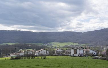 Un pueblo del valle de Ulzama rodeado de prados verdes y montes boscosos.