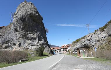 Peña rocosa prominente junto a carretera en Vidangoz, con casas tradicionales y vegetación pirenaica de fondo.