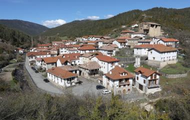Vista panorámica de Vidangoz con casas de tejados rojos, iglesia fortificada y montañas boscosas de fondo en el Pirineo navarro.