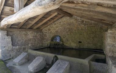 Interior de lavanderia histórica del Valle de Araitz con piedras, canalización de agua y vigas de madera original.