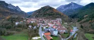 Vue aérienne d'Isaba entourée de montagnes boisées et de sommets rocheux, village pyrénéen dans une vallée à l'architecture traditionnelle.