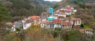 Village d'Uztarroz dans une vallée pyrénéenne avec des maisons traditionnelles aux toits rouges, une église en pierre et des forêts de montagne en arrière-plan en automne.