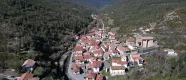 Vue aérienne du village de Vidangoz, entouré de forêts pyrénéennes, avec des maisons aux toits rouges et une vallée verte en arrière-plan.